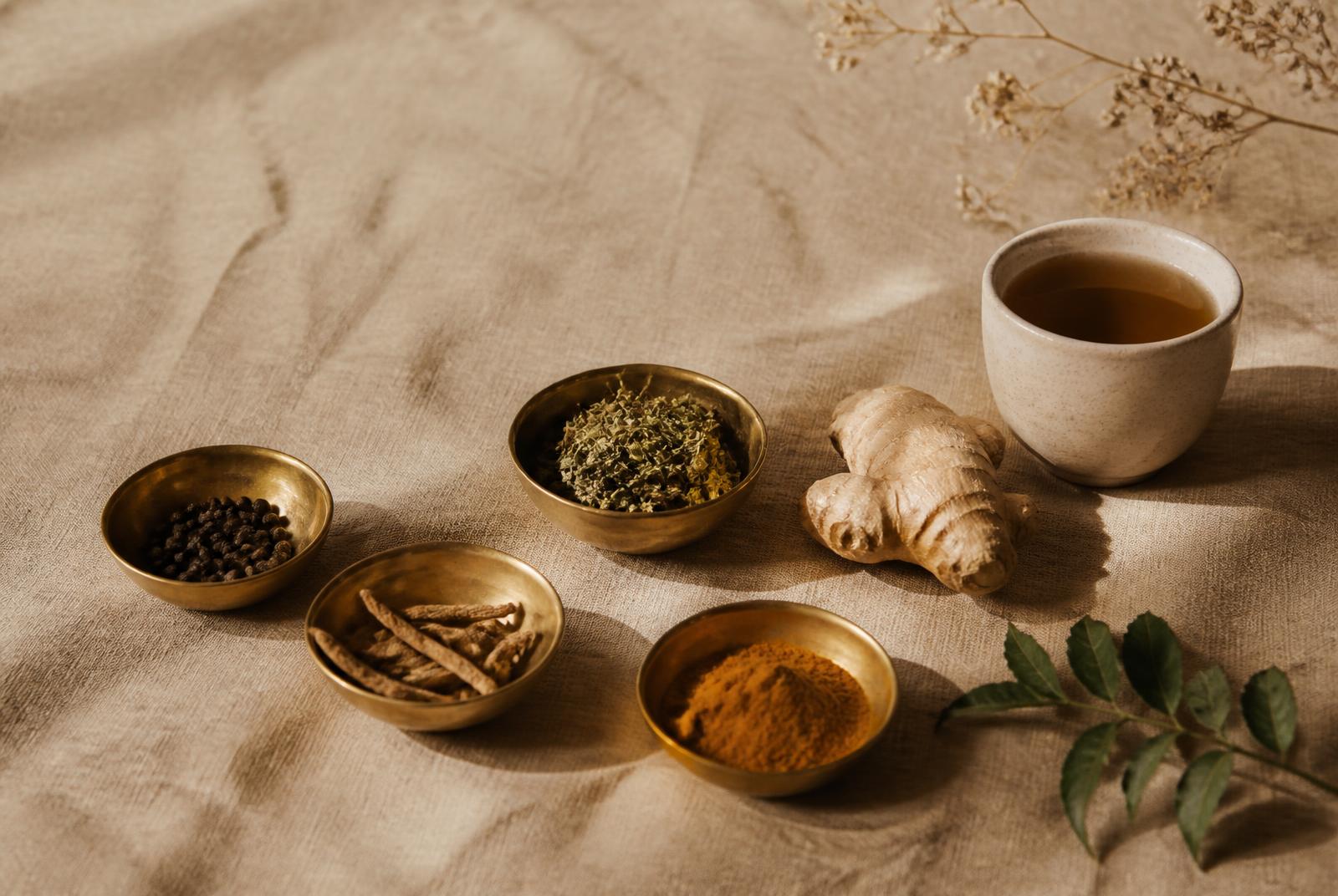 Bols de laiton, épices ayurvédiques et infusion posés sur une toile de lin naturelle
